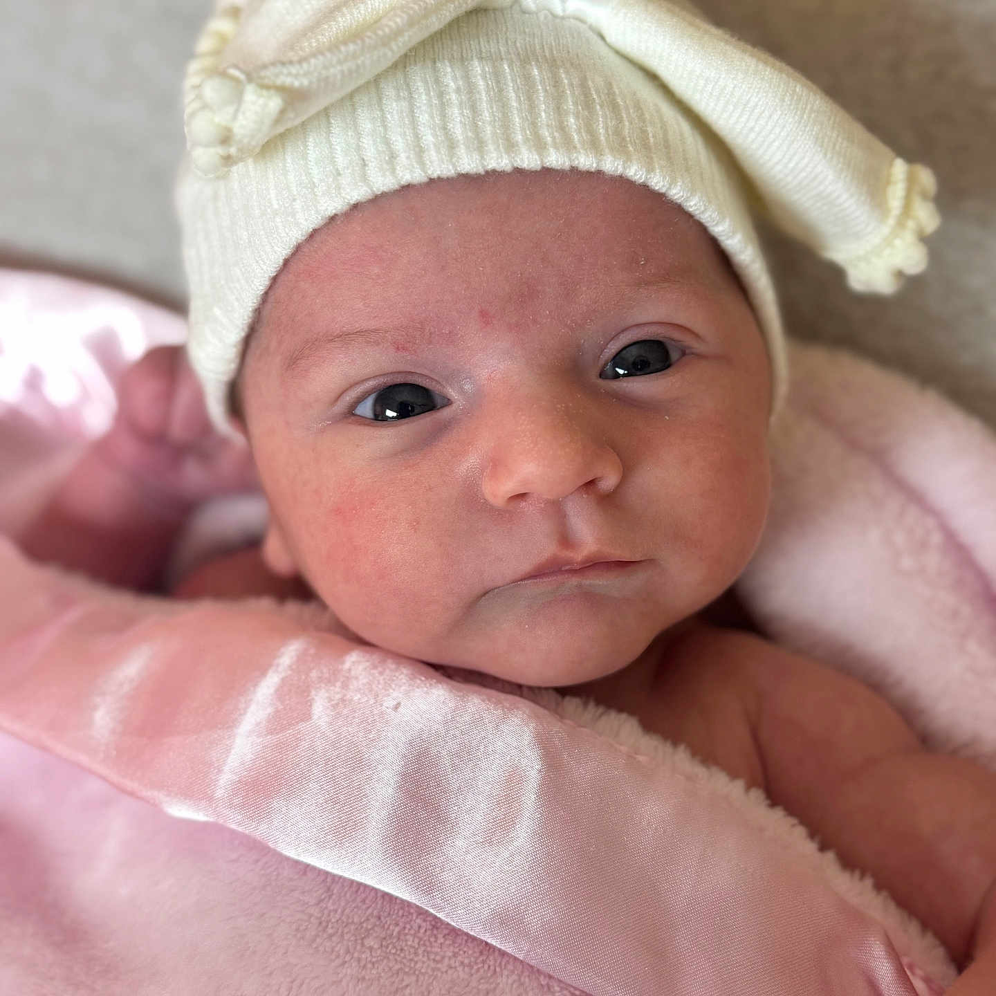 Cattaleya is registered to the contest to win money with this photo: baby, blanket, child, close_up, cute, expression, eyes, face, hat, headwear, indoors, infant, knit_hat, newborn, person, pink_blanket, portrait, skin, soft, warm