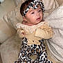 Marykate is registered to the contest to win money with this photo: baby, infant, headband, leopard_print, clothing, couch, pillow, soft_fabric, curious, portrait, indoor, child, cute, fashion, cozy, seated, person, young, comfortable, expression