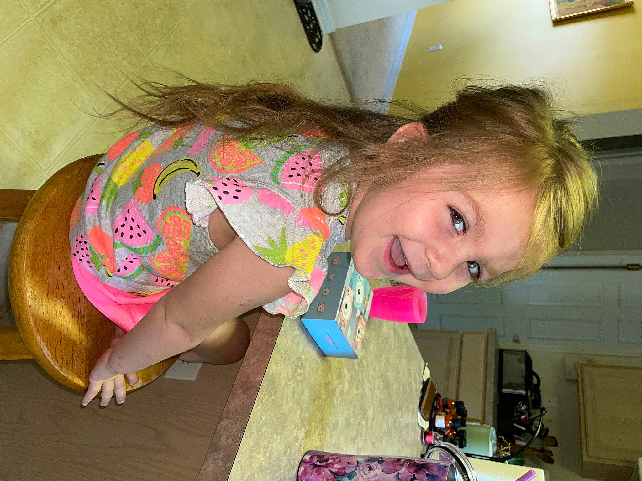 Ophelia is registered to the contest to win money with this photo: blond, child, eye, floor, flooring, fun, hairstyle, happy, head, human_leg, joy, kitchen_appliance, knee, long_hair, person, pink, room, sitting, smile, thigh
