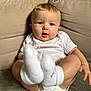baby, infant, child, couch, socks, onesie, blonde_hair, blue_eyes, indoor, portrait, cute, seated, soft_lighting, closeup, expression, comfort, home, person, skin, feet