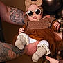 baby, child, sunglasses, headband, bow, tattoos, arm, balloons, brown_clothing, dress, socks, hands, portrait, indoor, cute, fashion, accessory, person, infant, celebration