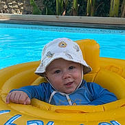 Siano a rejoint le concours — aidez-le/la à gagner de superbes lots ! baby, child, pool, water, inflatable_ring, hat, sun_hat, yellow, blue, smile, face, outdoor, summer, floating, cute, clothing, swimwear, happy, infant, vacation