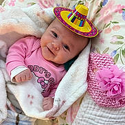 Savannah Casey is registered to the contest to win money with this photo: baby, smiling, blanket, pink_clothing, sombrero, floral_pattern, bedspread, pink_flower, knitted_hat, soft_texture, infant, cute, indoors, lying_down, cozy, portrait, child, happy, cute_accessory, bottle