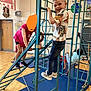 child, boy, indoor, playground, climbing, metal_bars, play_mats, school, wood_floor, jeans, tshirt, smile, happy, play, fun, activity, gym, friends, casual_clothing, kids