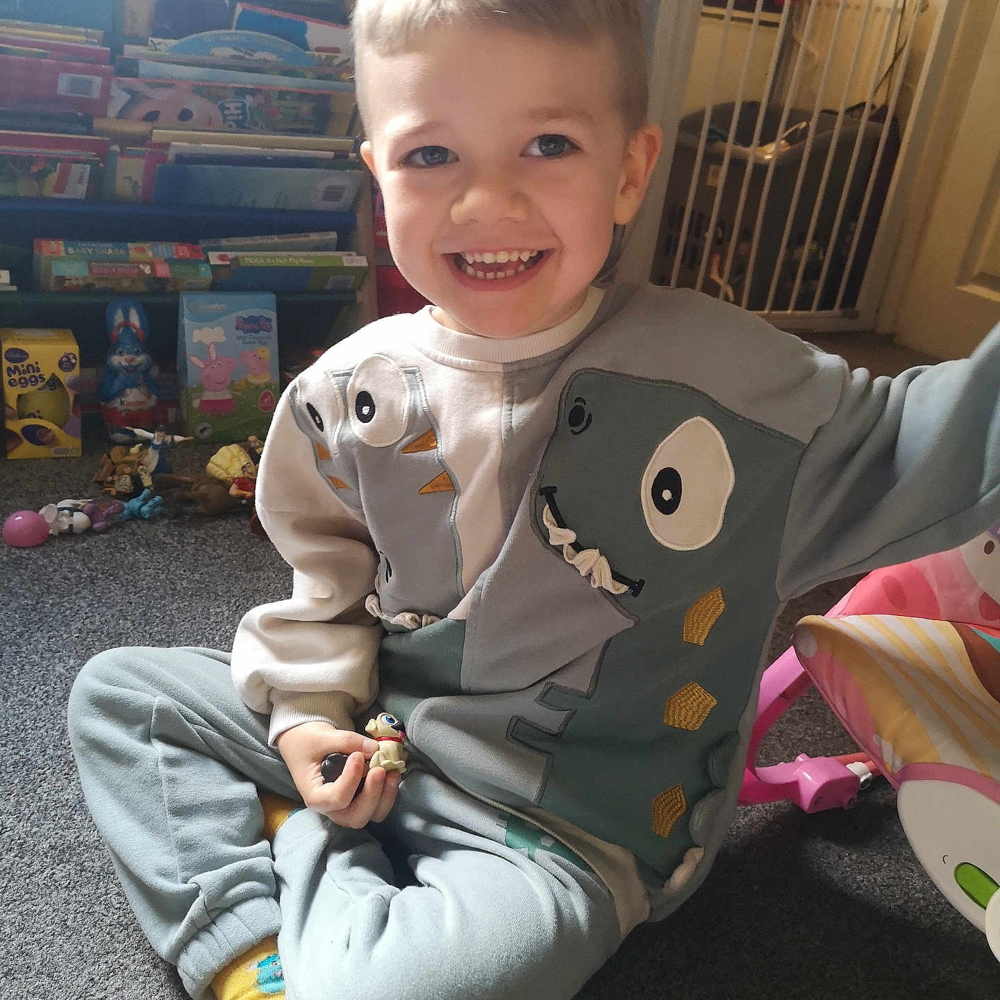 Cain-Leigh is registered to the contest to win money with this photo: baby_gate, books, boy, carpet, casual_clothing, child, childhood, cross_legged, dinosaur_sweatshirt, floor, furniture, happy, home, indoor, playroom, playtime, short_hair, smiling, toy, yellow_socks