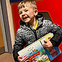 child, boy, smiling, books, jacket, indoor, red_wall, holding, happy, portrait, short_hair, casual_clothing, education, learning, reading, colorful, young, person, cute, playful