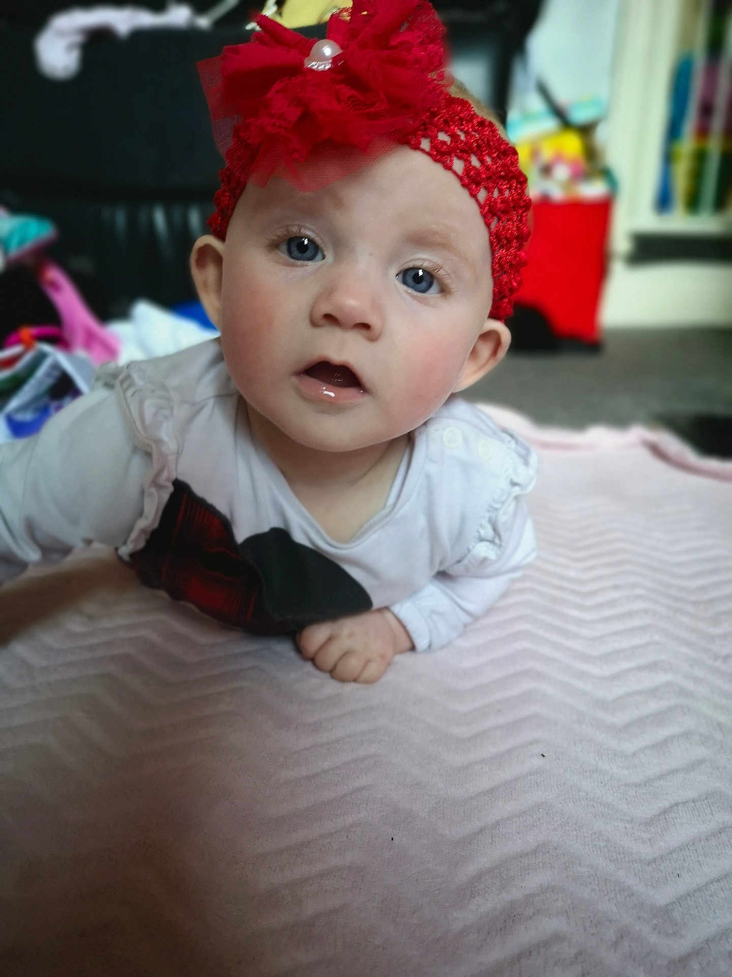 Bethany is registered to the contest to win money with this photo: baby, child, headband, red, blue_eyes, blanket, indoor, curious, face, person, soft_texture, clothing, long_sleeve, infant, focus, candid, closeup, expression, cute, toddler