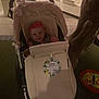 Bethany is registered to the contest to win money with this photo: baby, stroller, infant, pink_headband, smiling, indoor, tree_trunk, sign, cream_color, fabric, child, cute, fluffy_trim, person, seat, display_case, floor, toy, happy, young