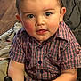 toddler, child, plaid_shirt, couch, blanket, indoor, portrait, cute, face, hands, eyes, rosy_cheeks, short_hair, holding, clothing, casual, seated, cozy, home, curious