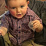 toddler, child, bubble, brush, plaid_shirt, pants, blanket, toy, indoor, curly_hair, face, hand, sitting, couch, playful, young_child, casual_clothing, closeup, expression, home