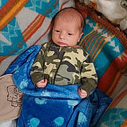 Theon is registered to the contest to win money with this photo: baby, infant, blanket, camouflage, clothing, fleece, pattern, paw_prints, person, newborn, cozy, lying_down, cute, warm, indoor, child, portrait, small_hands, sleepwear, soft