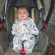 Theon joined the competition — help win amazing prizes! baby, car_seat, infant, onesie, mickey_mouse, child, floor, wooden_floor, seatbelt, strapped_in, indoor, cute, clothing, person, young_child, car_seat_interior, baby_girl, baby_boy, sitting, expression