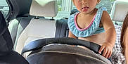Juliet is registered to the contest to win money with this photo: toddler, child, car, car_seat, interior, tongue_out, playful, person, seat, headrest, window, daylight, casual_clothing, hair_tie, backseat, vehicle, young_child, cute, portrait, funny_expression