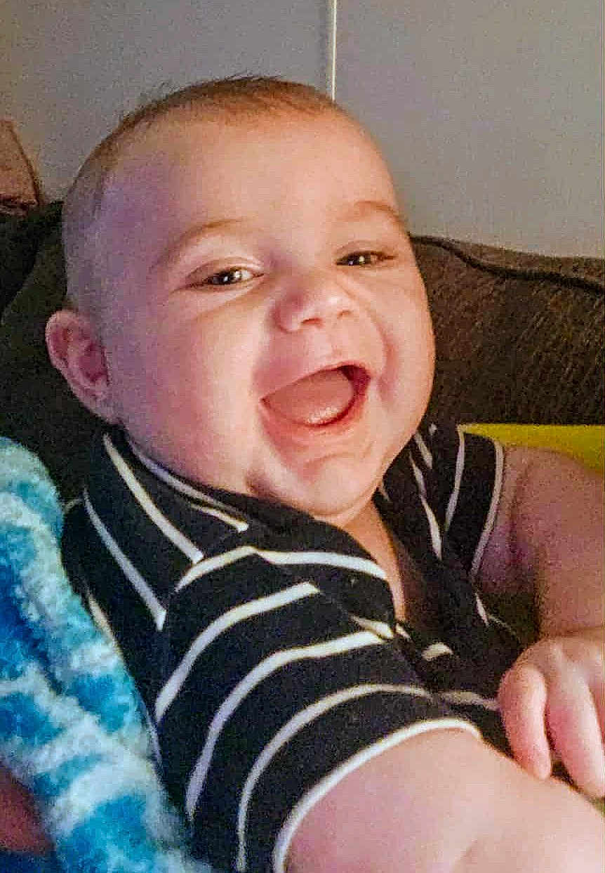 Johnny joined the competition — help win amazing prizes! baby, smiling, happy, child, infant, striped_shirt, face, mouth_open, couch, blanket, indoor, portrait, cute, young_child, cheerful, person, skin, head, arm, baby_clothes