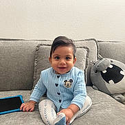 Ezhaan is registered to the contest to win money with this photo: baby, child, smiling, blue_sweater, mickey_mouse, couch, gray_cushions, plush_hippo, yellow_cap, tablet, indoor, happy, sitting, person, face, cute, home, cozy, soft_lighting, casual