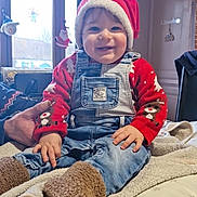 Maëvan participe au concours pour gagner de l'argent avec cette photo : baby, bodypart, bonnet, cap, clothing, coat, couch, face, finger, furniture, hand, hat, head, jacket, jeans, pants, person, photography, portrait, sitting