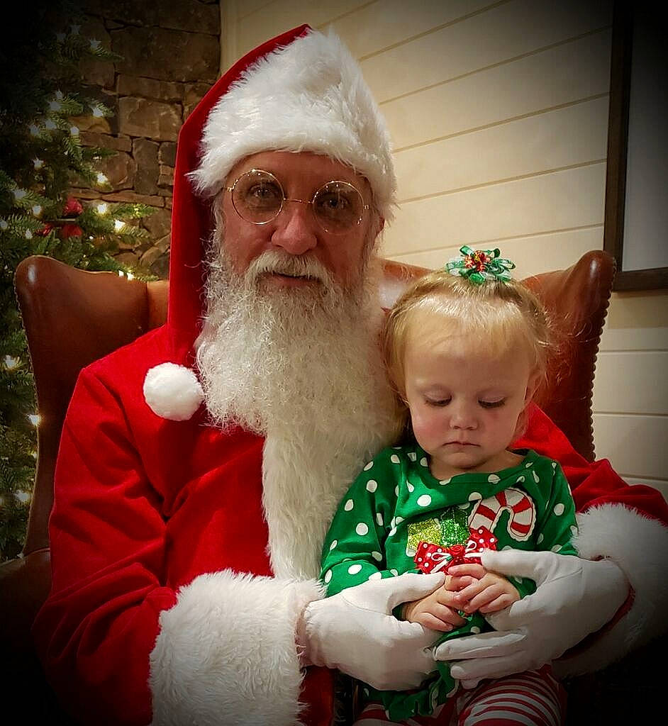 Kenzie is registered to the contest to win money with this photo: beard, christmas, christmas_eve, event, facial_hair, fictional_character, grandparent, headwear, holiday, lap, person, santa_claus