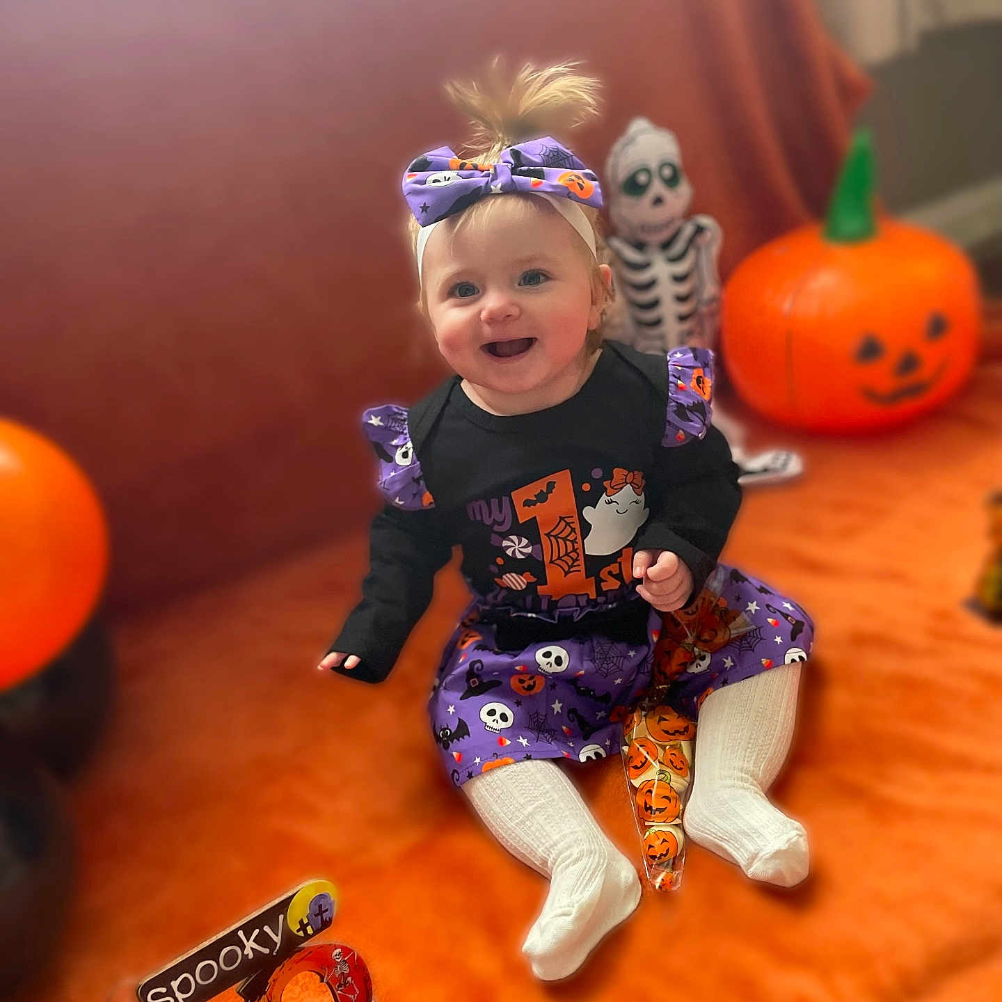 Savannah-Rae is registered to the contest to win money with this photo: baby, background_blur, child, costume, cute, decoration, festive, halloween, happy, headband, holiday, indoor, orange, pumpkin, purple, sitting, skeleton, smile, toy, white_socks
