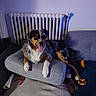 dog, couch, radiator, toy, bone, carpet, indoor, pet, relaxed, tongue_out, furniture, playful, brown_fur, black_fur, white_fur, paw, snout, living_room, cozy, resting