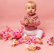 Julya participe au concours pour gagner de l'argent avec cette photo : baby, child, pink_background, pink_sweater, white_leggings, flowers, sitting, portrait, cute, indoor, studio, infant, flower_petals, soft_lighting, looking_at_camera, barefoot, blond_hair, young_child, adorable, smiling