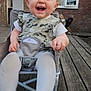 baby, child, smiling, happy, mickey_mouse, dress, curly_hair, chair, outdoor, wooden_deck, building, window, door, person, tights, feet, hand, seatbelt, playful, young