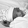 newborn, baby, sleeping, infant, portrait, black_and_white, blanket, bed, bedding, peaceful, resting, face, hand, closed_eyes, indoors, cozy, soft_lighting, nursery, swaddled, photography
