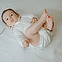 baby, bare_feet, child, curly_hair, cute, expression, face, foot, hand, indoors, infant, looking_up, lying_down, newborn, playful, portrait, skin, soft_lighting, textured_surface, white_onesie