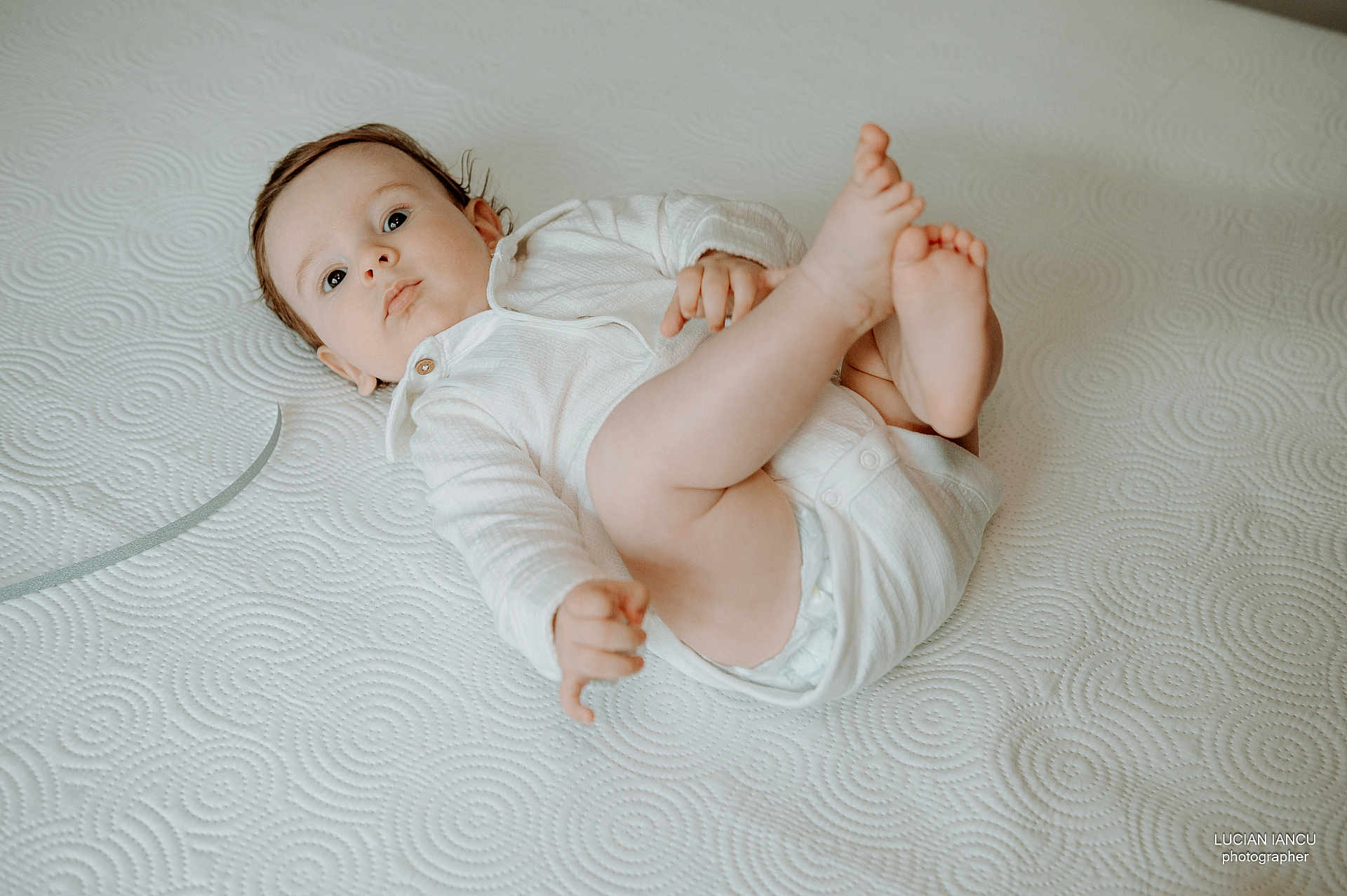 Cassian Stefan a rejoint le concours — aidez-le/la à gagner de superbes lots ! baby, bare_feet, child, curly_hair, cute, expression, face, foot, hand, indoors, infant, looking_up, lying_down, newborn, playful, portrait, skin, soft_lighting, textured_surface, white_onesie