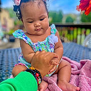 Alaina joined the competition — help win amazing prizes! baby, child, hand, bracelets, pink_bows, curly_hair, blanket, outdoor, table, flower, green_sleeve, skin, infant, holding_hand, person, cute, sitting, colorful, nature, portrait