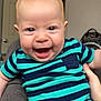 baby, child, smiling, indoor, person, clothing, striped_clothing, onesie, happy, face, head, skin, hand, leg, door, furniture, room, background, blue, green
