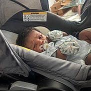 Jacari joined the competition — help win amazing prizes! baby, car_seat, pacifier, mittens, infant, indoor, person, cute, child, clothing, face, expression, furniture, baby_gear, soft_lighting, portrait, young_child, resting, closeup, adorable