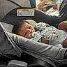 baby, car_seat, pacifier, mittens, infant, indoor, person, cute, child, clothing, face, expression, furniture, baby_gear, soft_lighting, portrait, young_child, resting, closeup, adorable