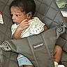 Jacari joined the competition — help win amazing prizes! baby, infant, babybjorn, carrier, clothing, dinosaur_pattern, socks, person, indoor, seat, resting, curious, young_child, cute, expression, fabric, soft, comfortable, child, newborn