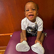 Timothy joined the competition — help win amazing prizes! toddler, child, smiling, white_shoes, purple_bench, wooden_wall, happy, sitting, casual_clothing, indoor, person, cute, young_child, footwear, holding, portrait, bright, cheerful, small_person, baby