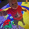 toddler, child, red_shirt, mickey_mouse, birthday_shirt, holding_hand, colorful_floor, illuminated_floor, ladybug, stars, curious, indoor, person, footwear, shorts, adult_hand, playful, bright_colors, expression, young_child