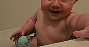 Kelly is registered to the contest to win money with this photo: baby, bare_chested, bath_time, bathroom, bathtub, child, close_up, eyes, face, green_object, hand, happy, home, indoor, infant, portrait, sitting, smiling, toy, wall