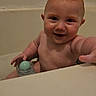baby, child, infant, smiling, bathroom, bathtub, bath_time, bare_chested, portrait, face, eyes, happy, sitting, toy, green_object, hand, indoor, home, wall, close_up