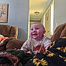 Kelly joined the competition — help win amazing prizes! baby, child, infant, smiling, happy, sitting, portrait, face, eyes, indoors, living_room, sofa, blanket, sunflower, floral_pattern, clothing, home, hallway, natural_light, photography