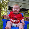 baby, child, infant, smiling, sitting, outdoor, backyard, lawn, blue_chair, red_shirt, legend_shirt, rv, camper, trees, grass, portrait, face, bare_feet, diaper, sunlight