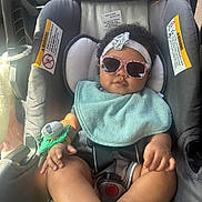 Kvori is registered to the contest to win money with this photo: accessory, baby, bib, car_seat, child, clothing, cute, foot, hand, headband, indoor, infant, pacifier, portrait, relaxing, seatbelt, smiling, sunglasses, sunlight, vehicle