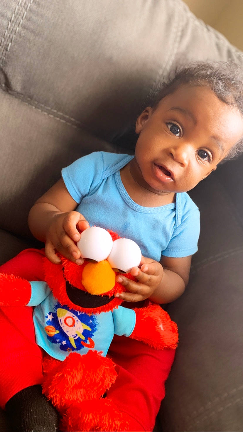 Jakobe is registered to the contest to win money with this photo: baby, baby_playing_with_toys, baby_products, baby_toys, child, orange, person, play, product, sitting, smile, stuffed_toy, textile, toddler, toy
