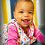 baby, child, smiling, crawling, colorful_clothing, floral_pattern, pink_sleeve, happy, face, eyes, mouth, teeth, indoor, vibrant_background, striped_background, person, portrait, cute, infant, playful