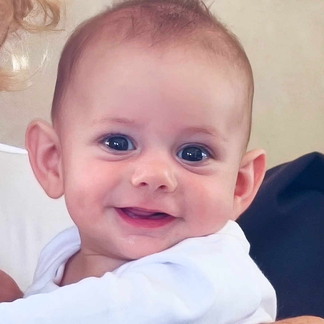 Léo participe au concours pour gagner de l'argent avec cette photo : arm, baby, background, bracelet, child, closeup, cute, expression, eyes, face, freckles, hair, happy, holding, infant, person, portrait, skin, smiling, white_clothing