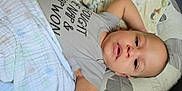 Omari is registered to the contest to win money with this photo: baby, infant, blanket, clothing, face, person, pillow, bed, lying_down, cute, skin, head, eyes, mouth, baby_garment, soft_texture, indoors, resting, young_child, expression