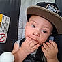 baby, child, cap, hat, car_seat, safety_harness, plush_toy, stuffed_animal, hand, fingers, face, eyes, infant, seat, clothing, cute, indoors, expression, person, young