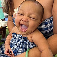 Alannah joined the competition — help win amazing prizes! baby, child, smiling, happy, person, face, flower, arm, hand, plaid_clothing, blue, green_bracelet, skin, mouth_open, eyes_closed, indoor, holding, cute, infant, joy