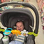 baby, stroller, toy, smile, infant, baby_bottle, child, shopping_aisle, clothing, store, happy, seat, person, indoor, retail, baby_toy, baby_clothes, colorful, cute, young_child