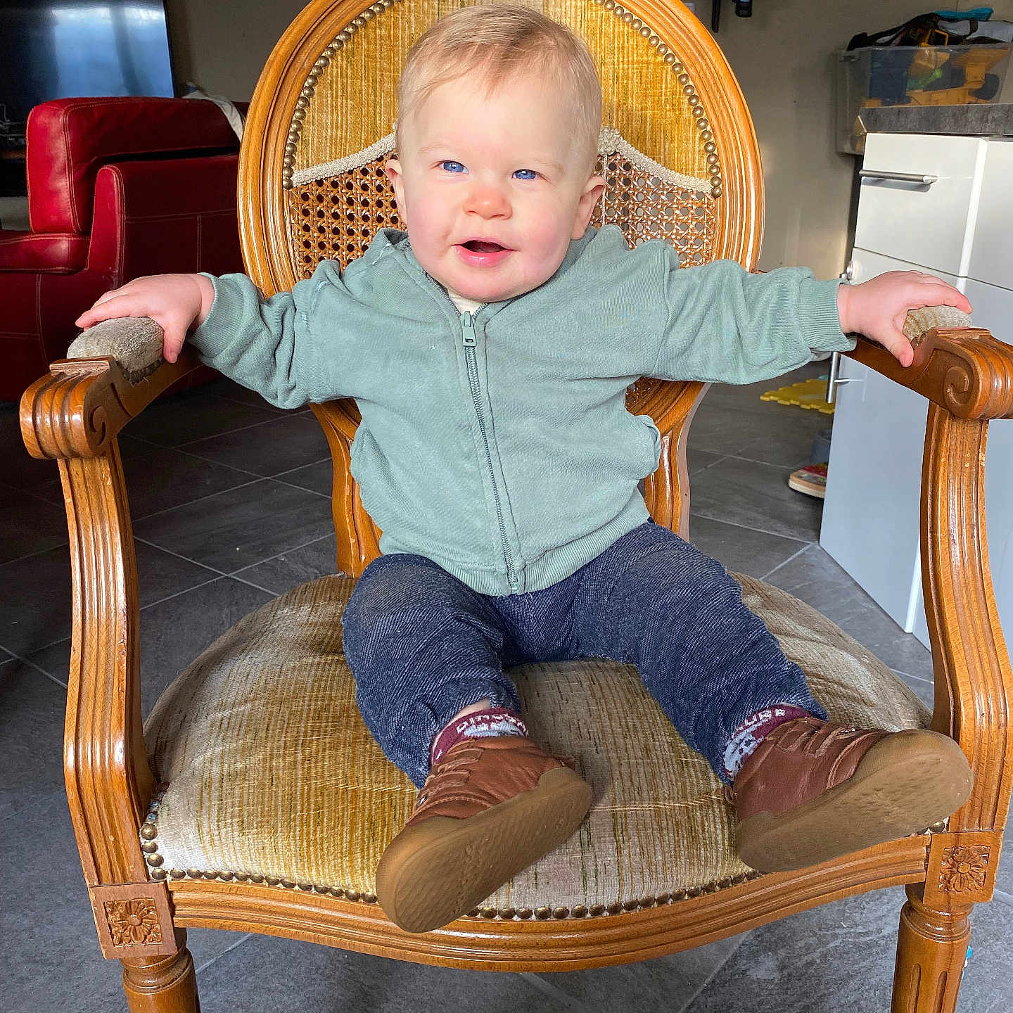 Tyler participe au concours pour gagner de l'argent avec cette photo : blue_eyes, casual, casual_clothing, chair, child, cute, floor_tiles, furniture, happy, home, indoor, living_room, person, short_hair, sitting, smiling, sneakers, toddler, wooden_chair, young_child