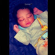 Kyaire is registered to the contest to win money with this photo: baby, sleeping, infant, blanket, plush_toy, clothing, cute, peaceful, face, head, hand, resting, indoors, soft_toy, child, young, portrait, comfort, love, dark_background