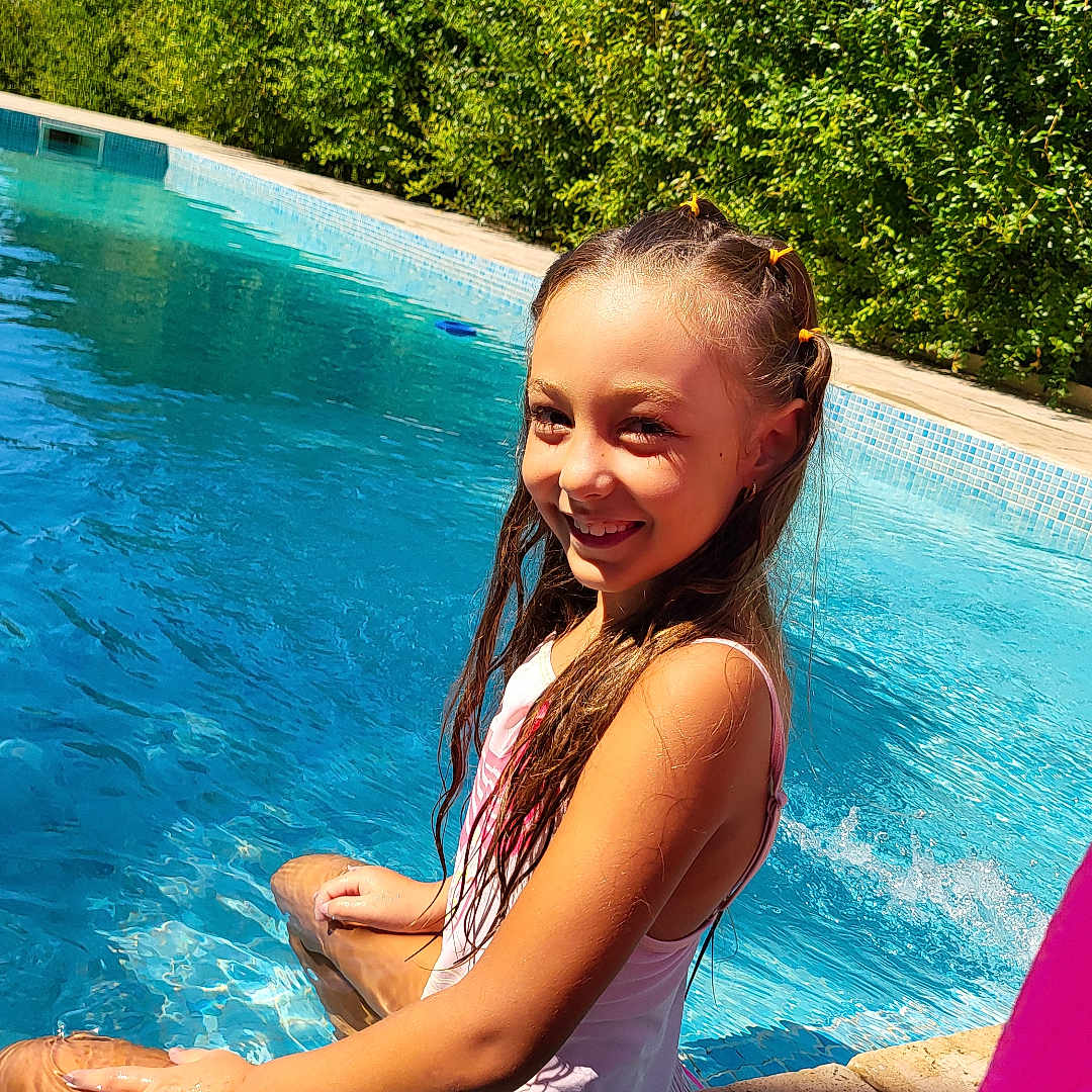 Noursine a rejoint le concours — aidez-le/la à gagner de superbes lots ! blue_sky, child, daytime, girl, happy, hedge, inflatable, nature, outdoor, pink, pool, recreation, relaxation, sitting, smile, summer, sunlight, swimsuit, water, wet_hair